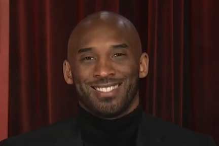 Kobe Bryant smiles in front of purple curtain